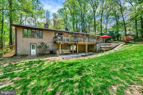 a view of house with a big yard and large trees