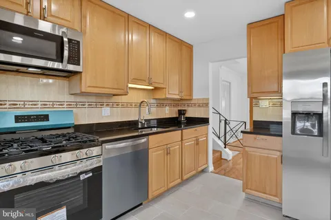 a kitchen with stainless steel appliances granite countertop a stove a sink and a refrigerator