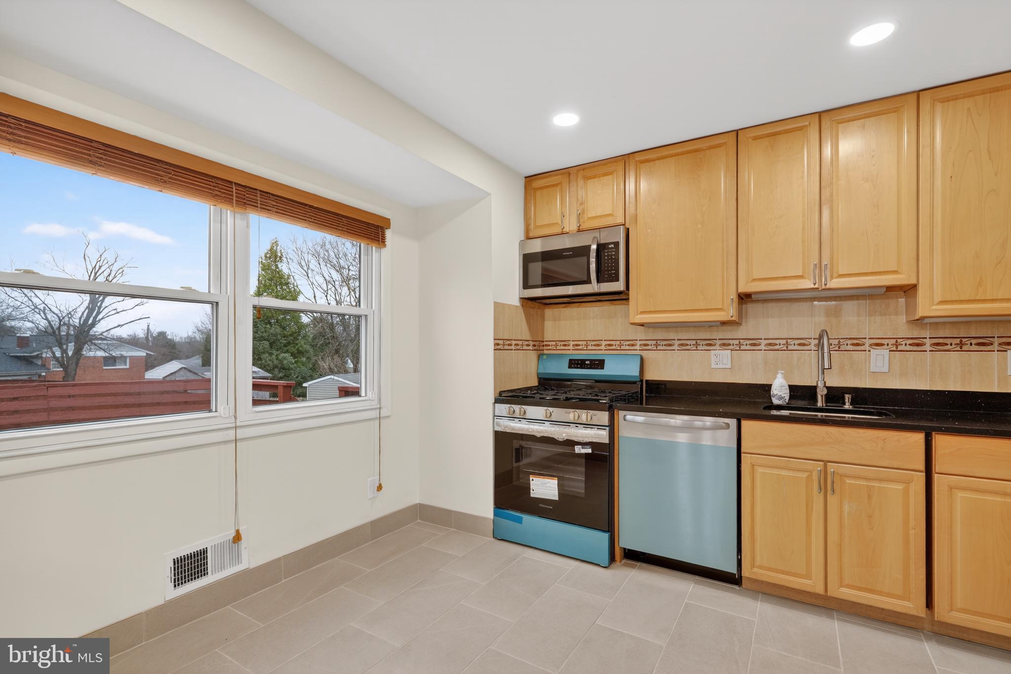 1132 Loxford Terrace Silver Spring, MD 20901 - Photo 8 of 30 a kitchen with stainless steel appliances granite countertop a stove a sink and a microwave