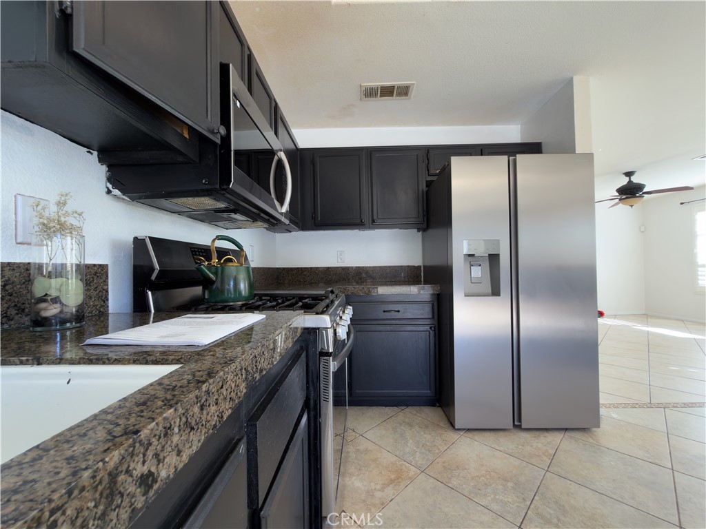 15036 Carrolton Street Adelanto, CA 92301 - Photo 3 of 23 a kitchen with stainless steel appliances granite countertop a sink a stove and a refrigerator