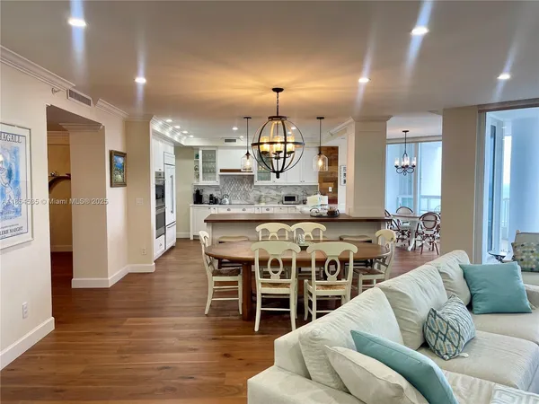 a living room with stainless steel appliances granite countertop furniture and wooden floor