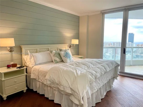 a spacious bedroom with a bed and a flat tv screen on the dresser