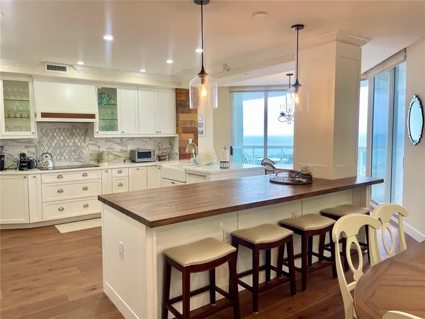 a kitchen with kitchen island granite countertop a table chairs sink and cabinets