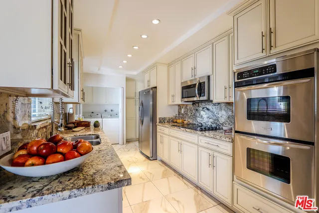 a kitchen with stainless steel appliances kitchen island granite countertop a stove refrigerator and microwave