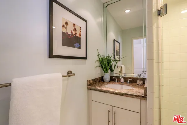 a bathroom with a granite countertop sink a mirror and a shower