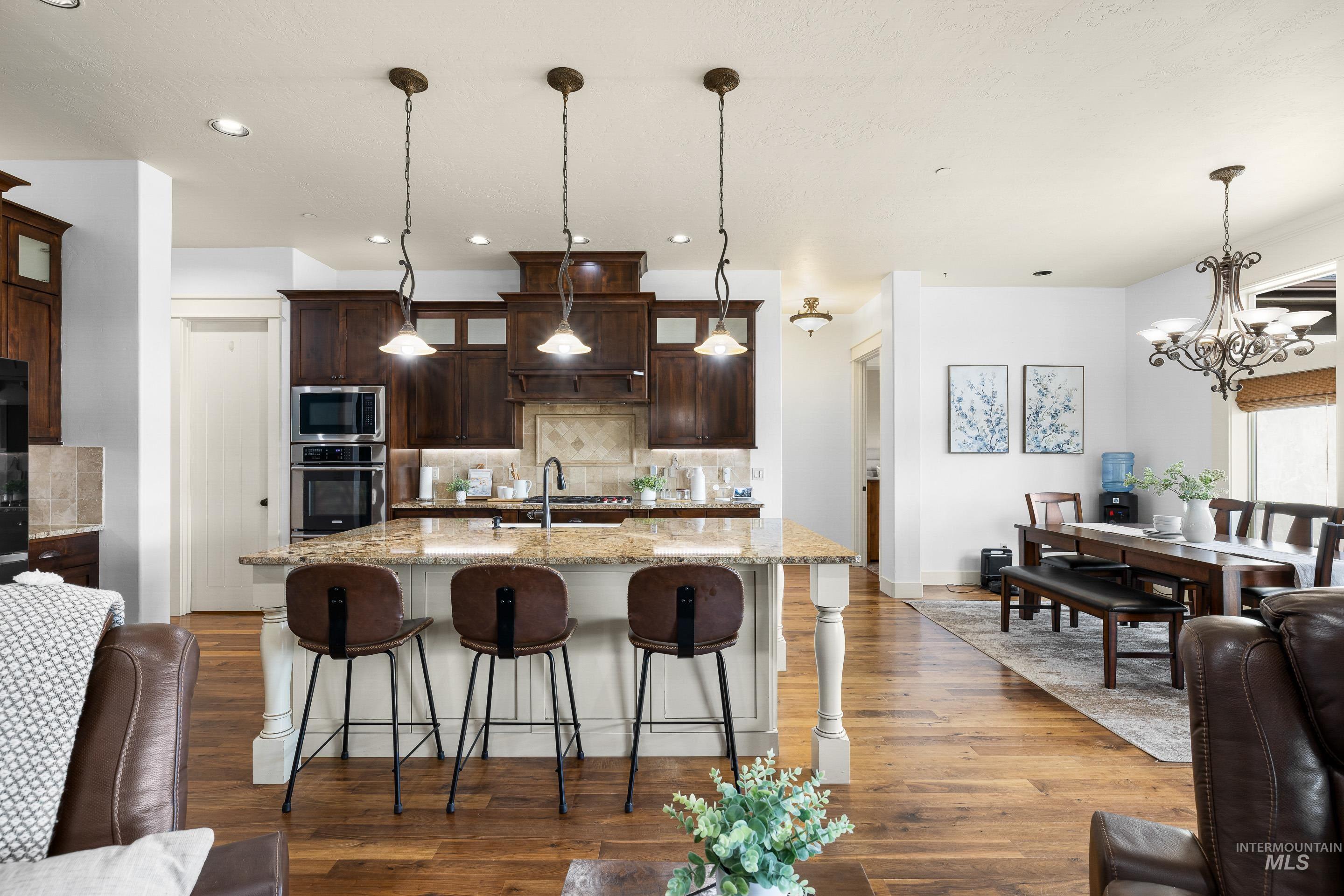 7521 North Grand Ridge Lane Eagle, ID 83616 - Photo 19 of 50 Kitchen with light stone countertops, dark wood-type flooring, dark wood finish cabinetry, and a kitchen breakfast bar