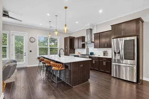 a kitchen with stainless steel appliances granite countertop a refrigerator a stove a sink dishwasher a refrigerator and a dining table with wooden floor