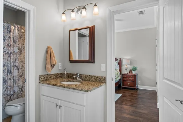 a en suite bathroom with a granite countertop sink and a mirror