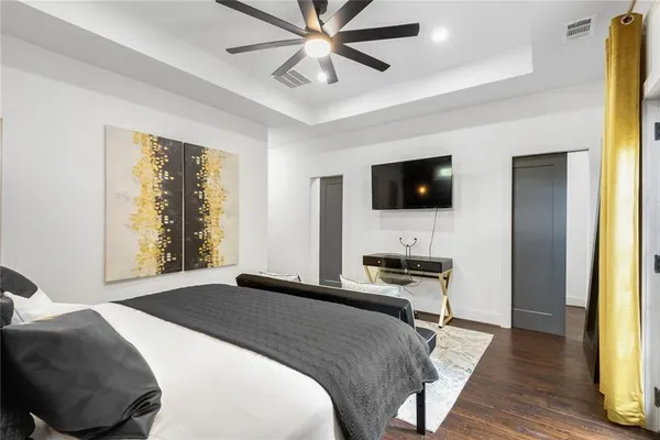 a bedroom with a bed and a flat tv screen on dresser