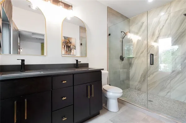 a bathroom with a double vanity sink toilet and shower