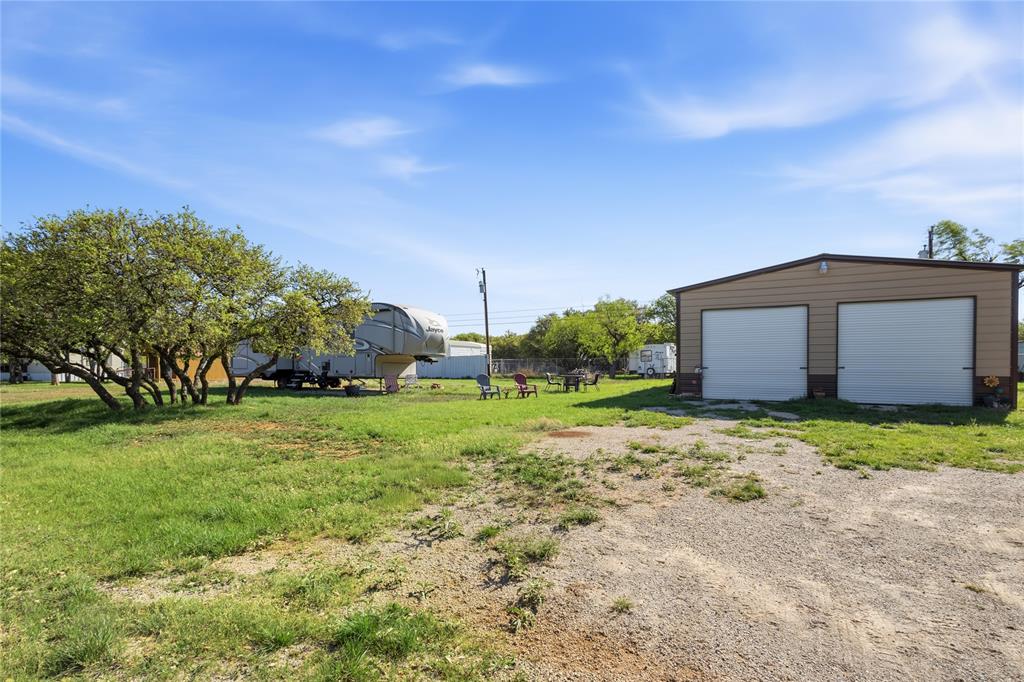 4441 Pawnee Drive May, TX 76857 - Photo 1 of 12 a backyard of a house with plants and large trees