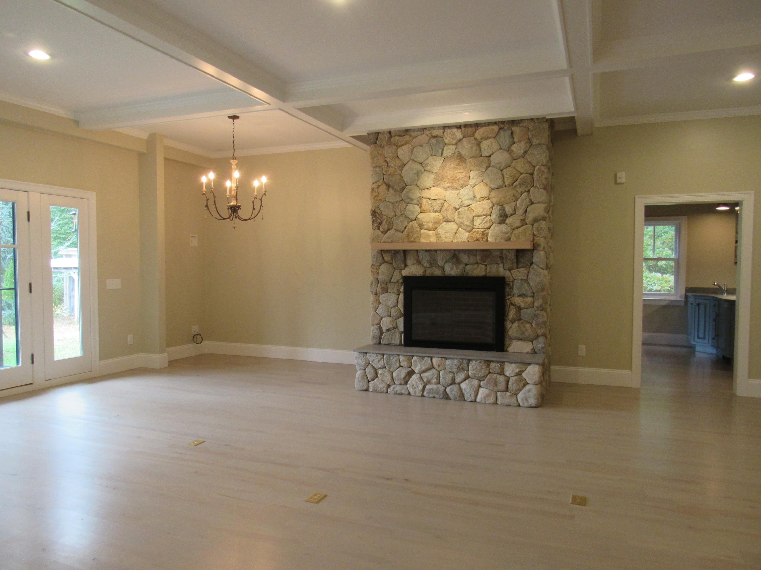 49-55 Rocky Point Road Bourne, MA 02532 - Photo 16 of 42 an empty room with a fireplace and chandelier