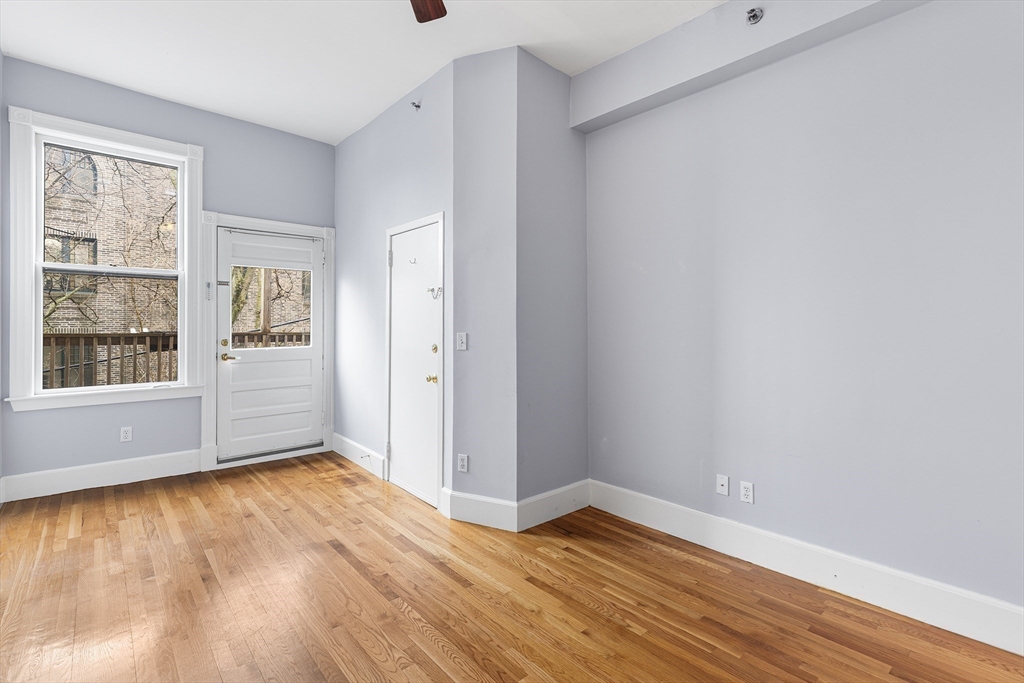 398 Broadway, Unit 2A Somerville, MA 02145 - Photo 17 of 25 a view of an empty room with wooden floor and a window