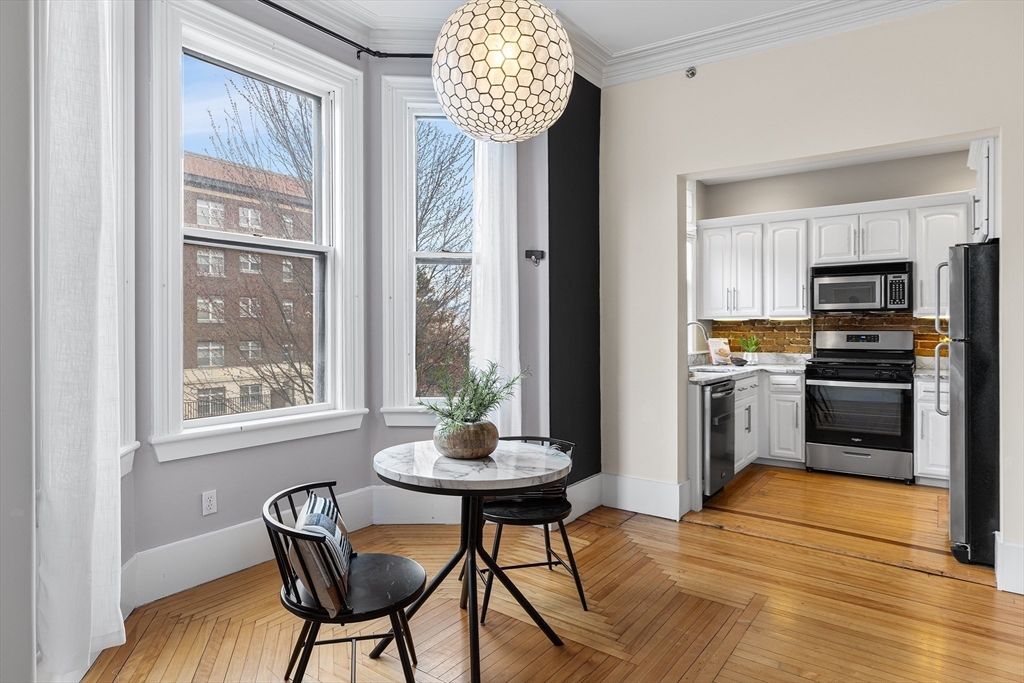 398 Broadway, Unit 2A Somerville, MA 02145 - Photo 6 of 25 a kitchen with granite countertop a table and chairs in it