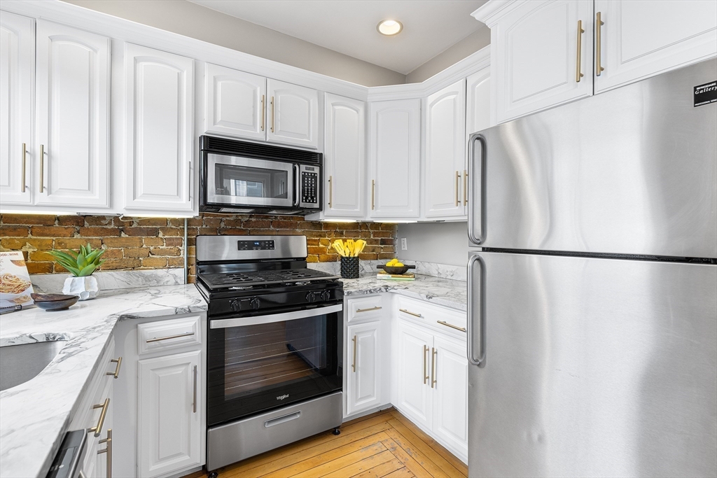 398 Broadway, Unit 2A Somerville, MA 02145 - Photo 9 of 25 a kitchen with white cabinets and white appliances