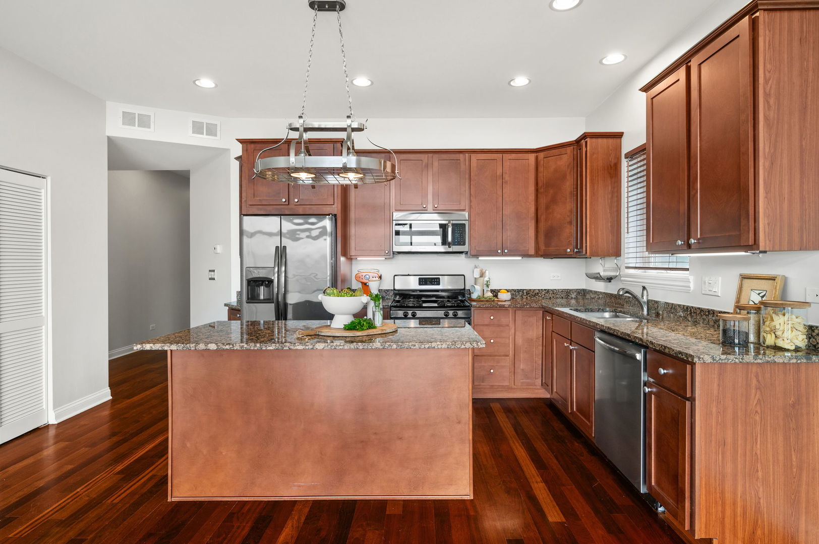 2847 North Pulaski Road, Unit 3S Chicago, IL 60641 - Photo 7 of 25 a kitchen with kitchen island granite countertop wooden cabinets stainless steel appliances a sink and a center island
