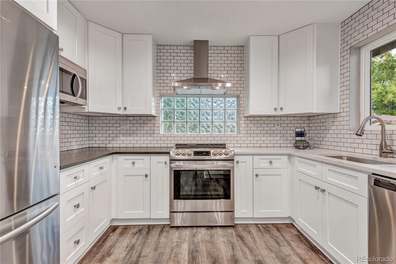 3880 Allison Street Wheat Ridge, CO 80033 - Photo 9 of 25 a kitchen with cabinets appliances a sink and a window