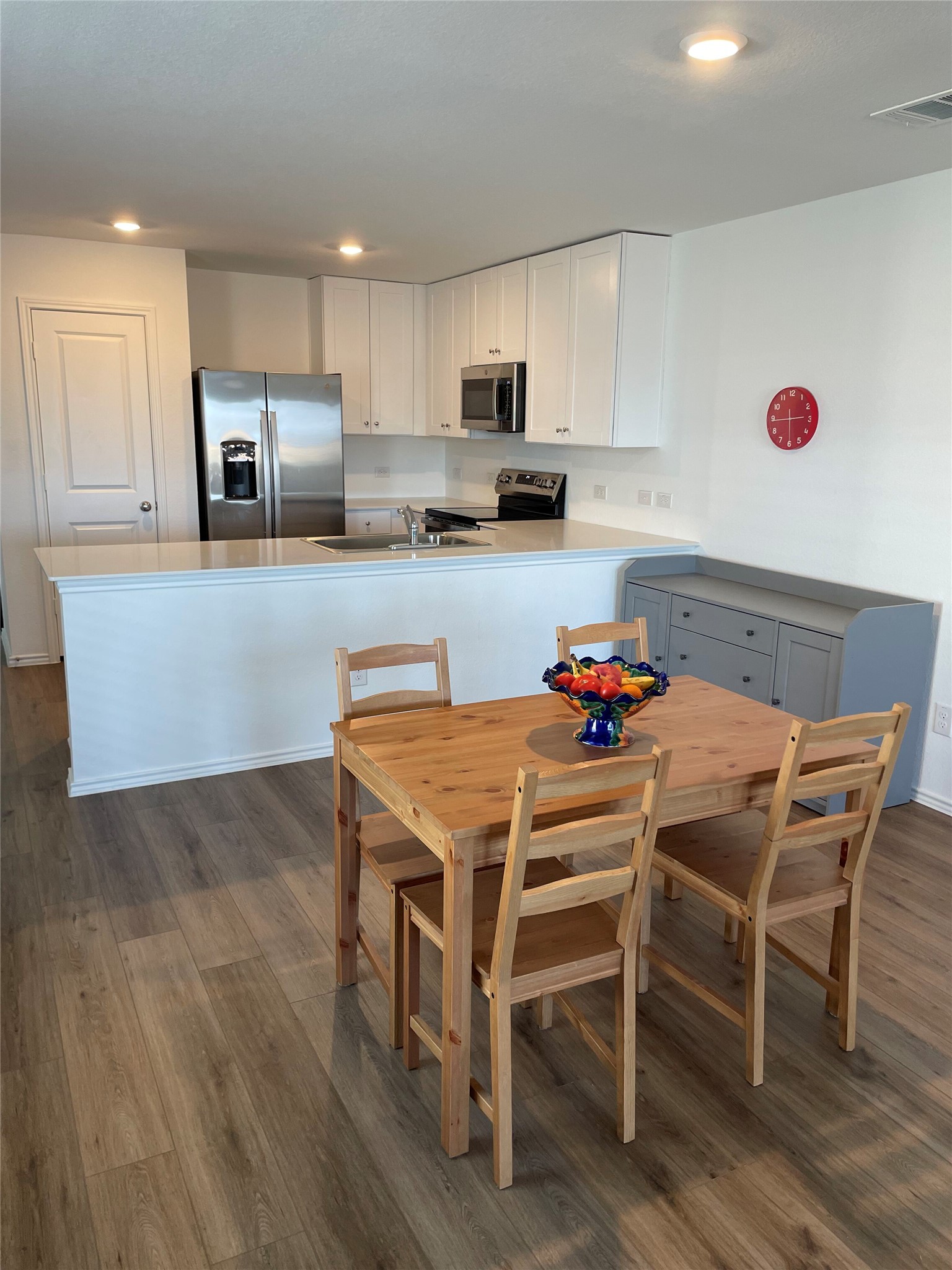 580 Rancho Del Cielo Loop Jarrell, TX 76537 - Photo 6 of 27 a kitchen with stainless steel appliances granite countertop a dining table chairs refrigerator and microwave