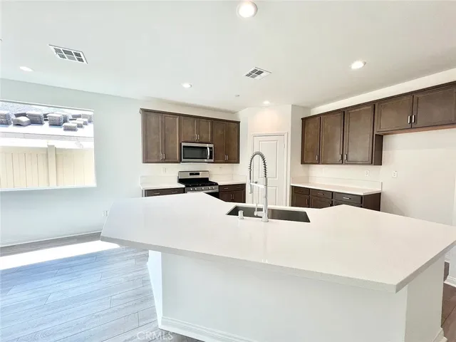 a kitchen with stainless steel appliances a sink a stove a refrigerator a center island and couches