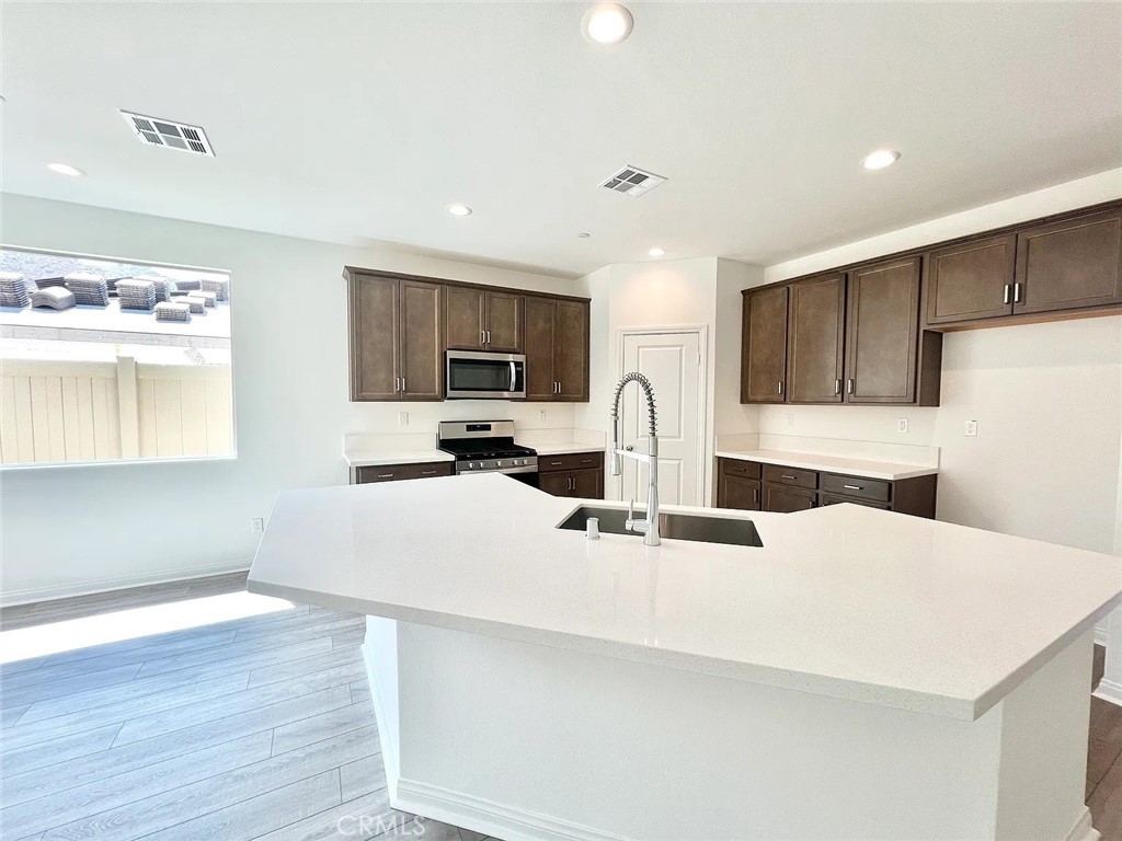 8285 Tristan Lane Riverside, CA 92507 - Photo 4 of 38 a kitchen with stainless steel appliances a sink a stove a refrigerator a center island and couches