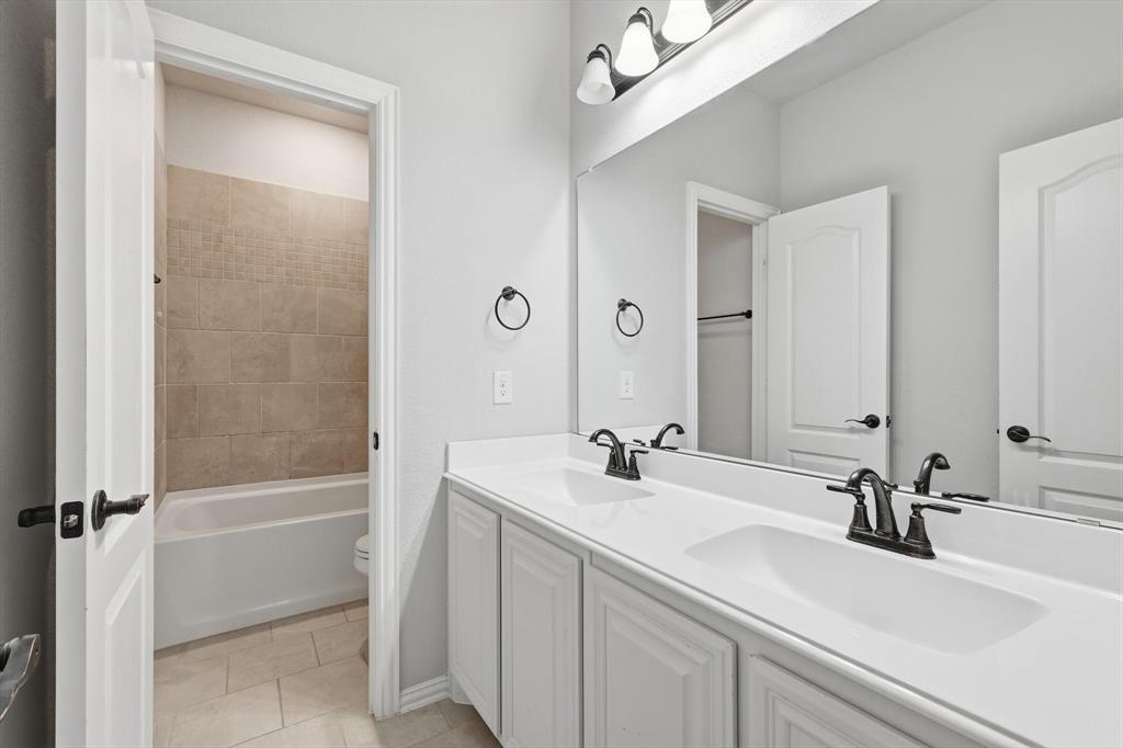 924 Timber Ridge Drive Justin, TX 76247 - Photo 27 of 32 Bathroom featuring a dual vanity with white cabinetry, integrated sinks, and black fixtures