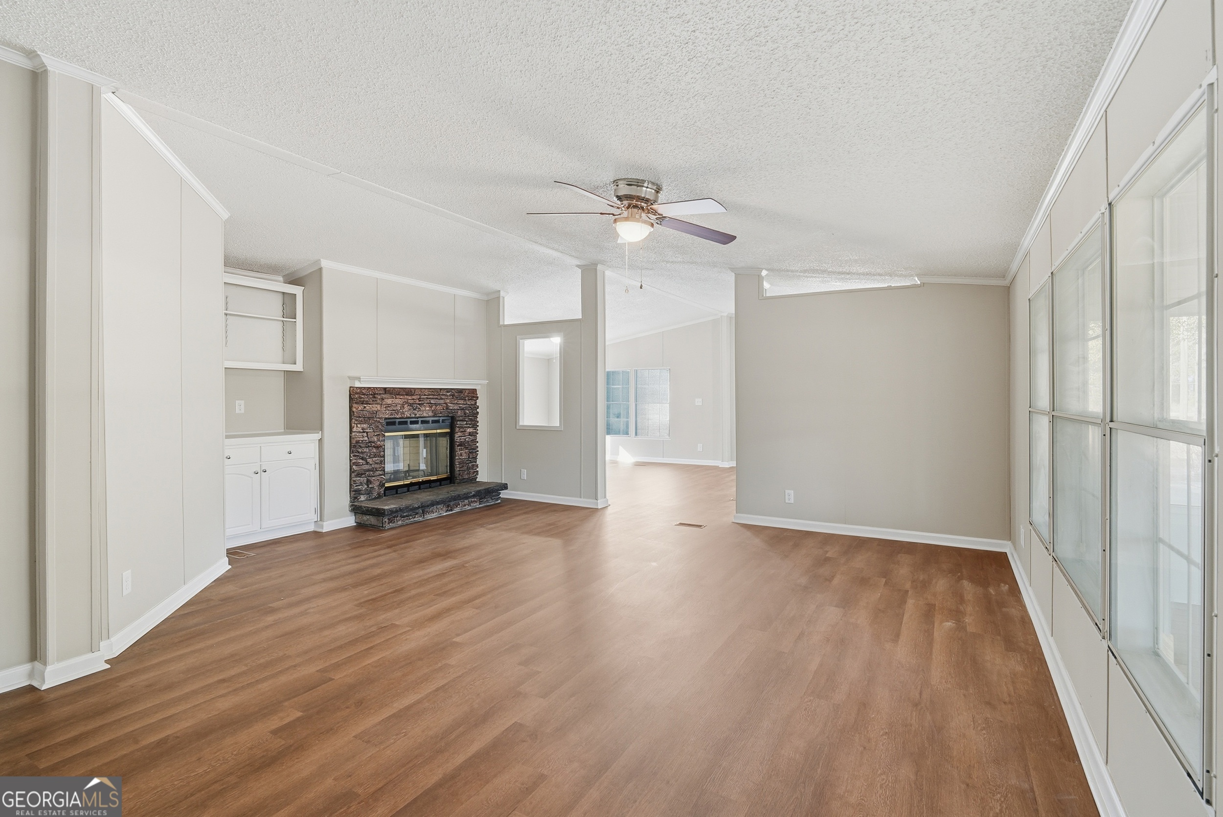 492 Doctortown Road Jesup, GA 31545 - Photo 6 of 25 an empty room with wooden floor fireplace and ceiling fan