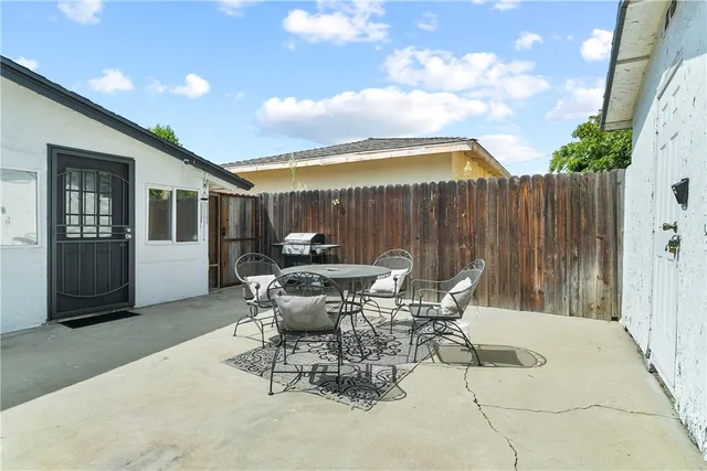 a view of a patio with table and chairs with wooden fence