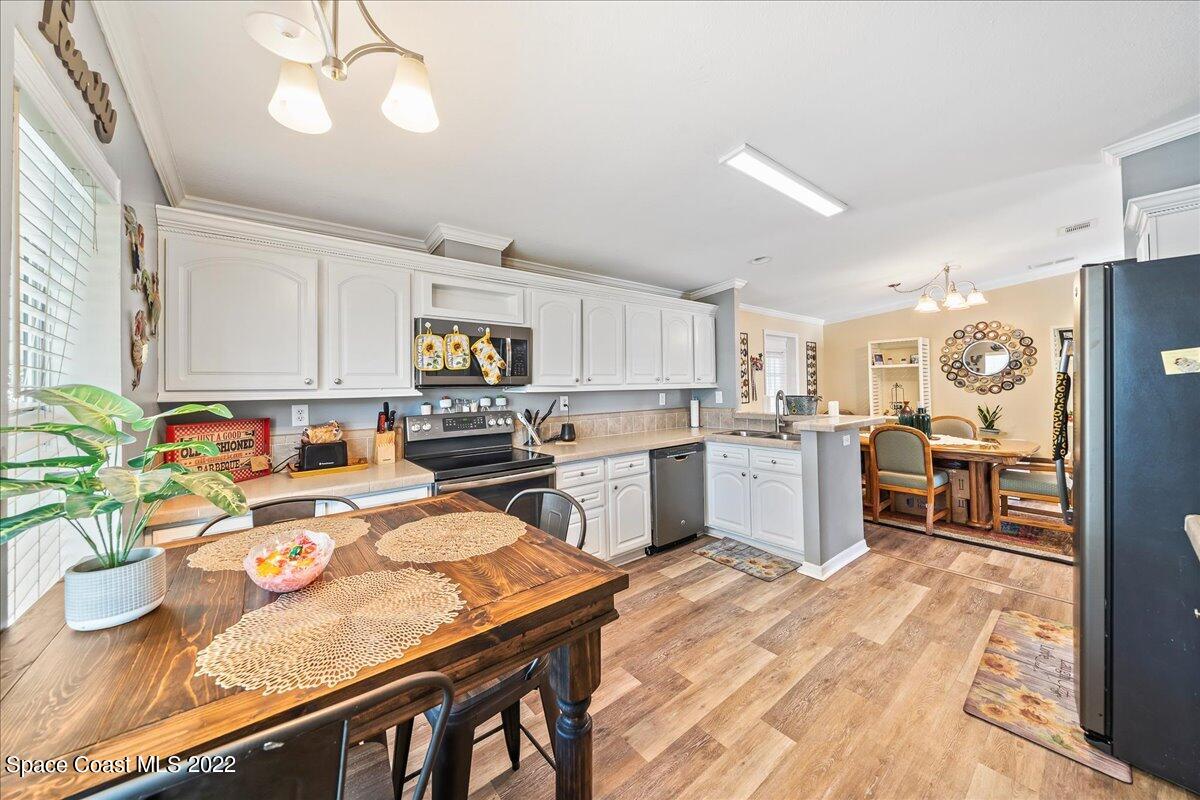 1017 Barefoot Circle Sebastian, FL 32976 - Photo 8 of 33 a open kitchen with stainless steel appliances granite countertop a stove refrigerator a sink dishwasher and white cabinets with wooden floor