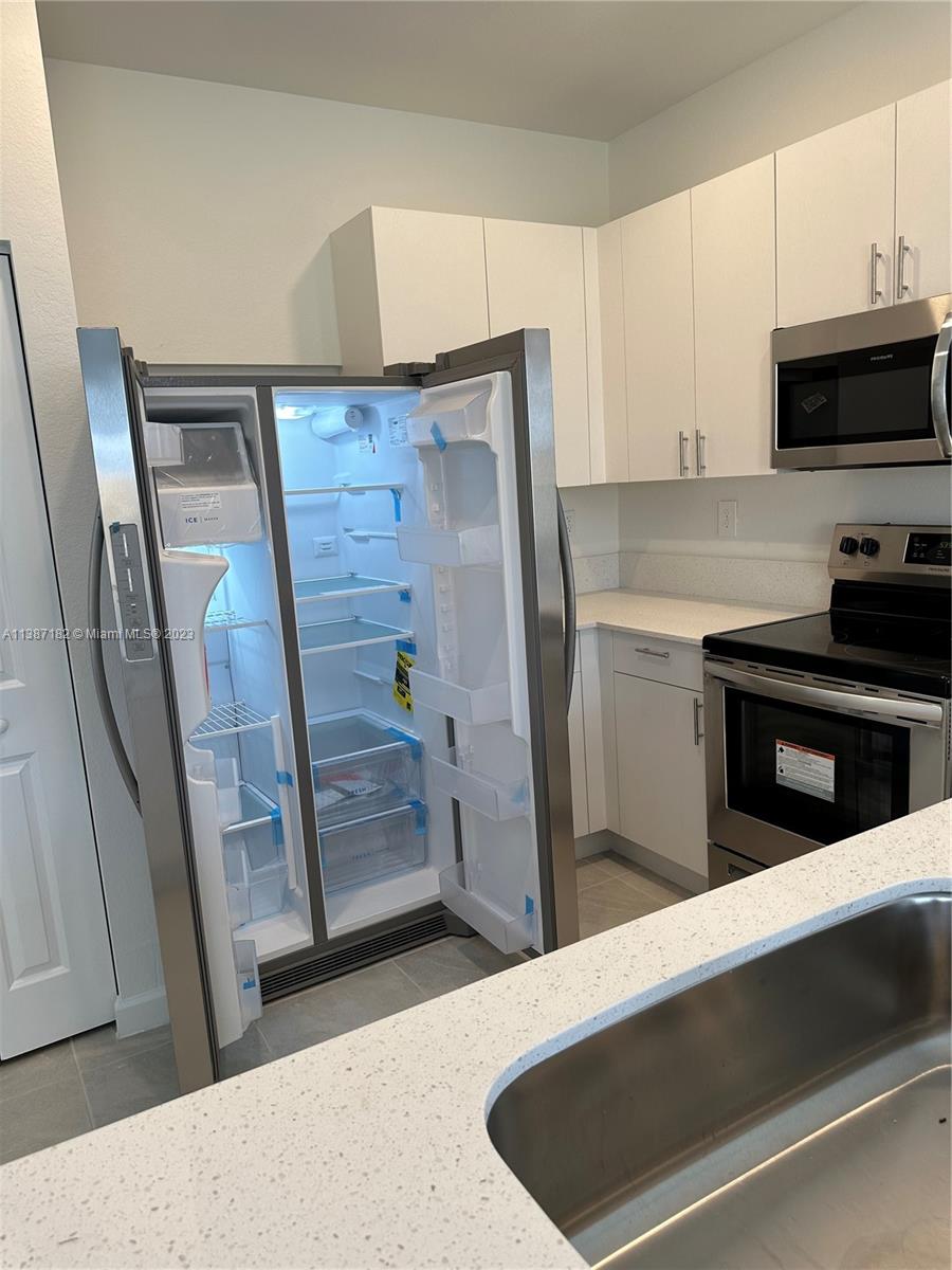 Miami-Dade County Homestead, FL 33032 - Photo 12 of 30 a kitchen with stainless steel appliances a refrigerator and a stove