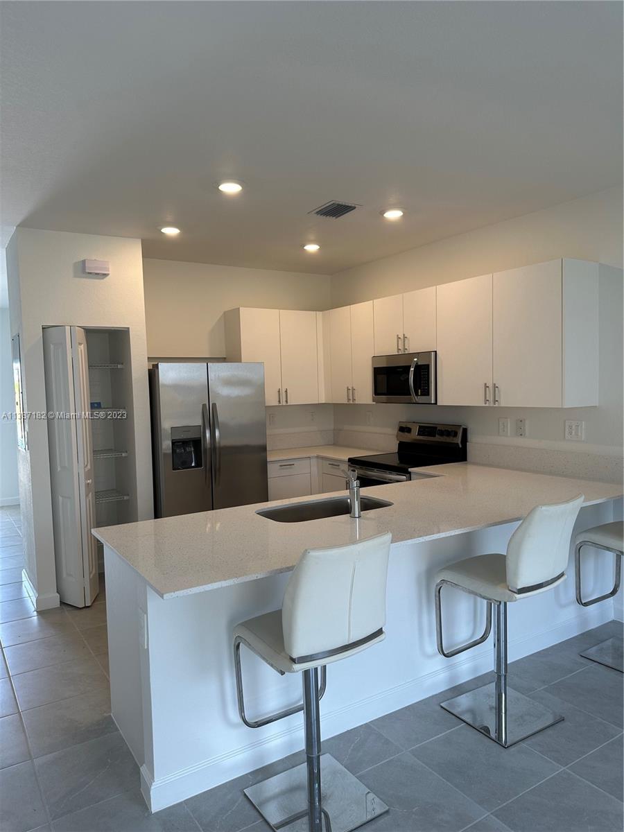 Miami-Dade County Homestead, FL 33032 - Photo 15 of 30 a kitchen with stainless steel appliances a refrigerator and a stove top oven