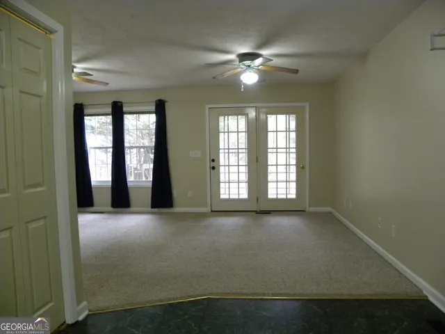 an empty room with chandelier fan and windows