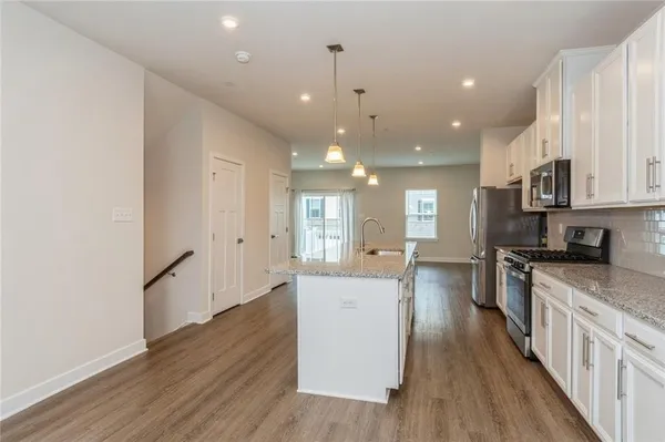 a large kitchen with stainless steel appliances granite countertop a lot of counter space and wooden floors