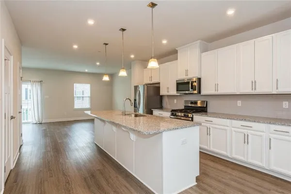 a kitchen with stainless steel appliances granite countertop a sink a stove and a wooden floors