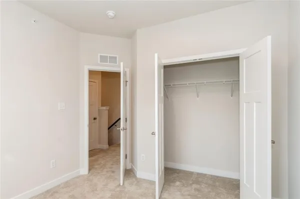 a view of an empty room with closet and a window