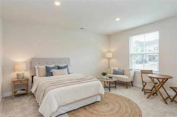 a bedroom with a bed a chair and next to a window