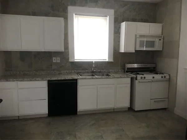 a kitchen with granite countertop white cabinets and white appliances