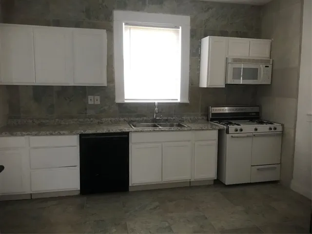 a kitchen with granite countertop white cabinets and white appliances