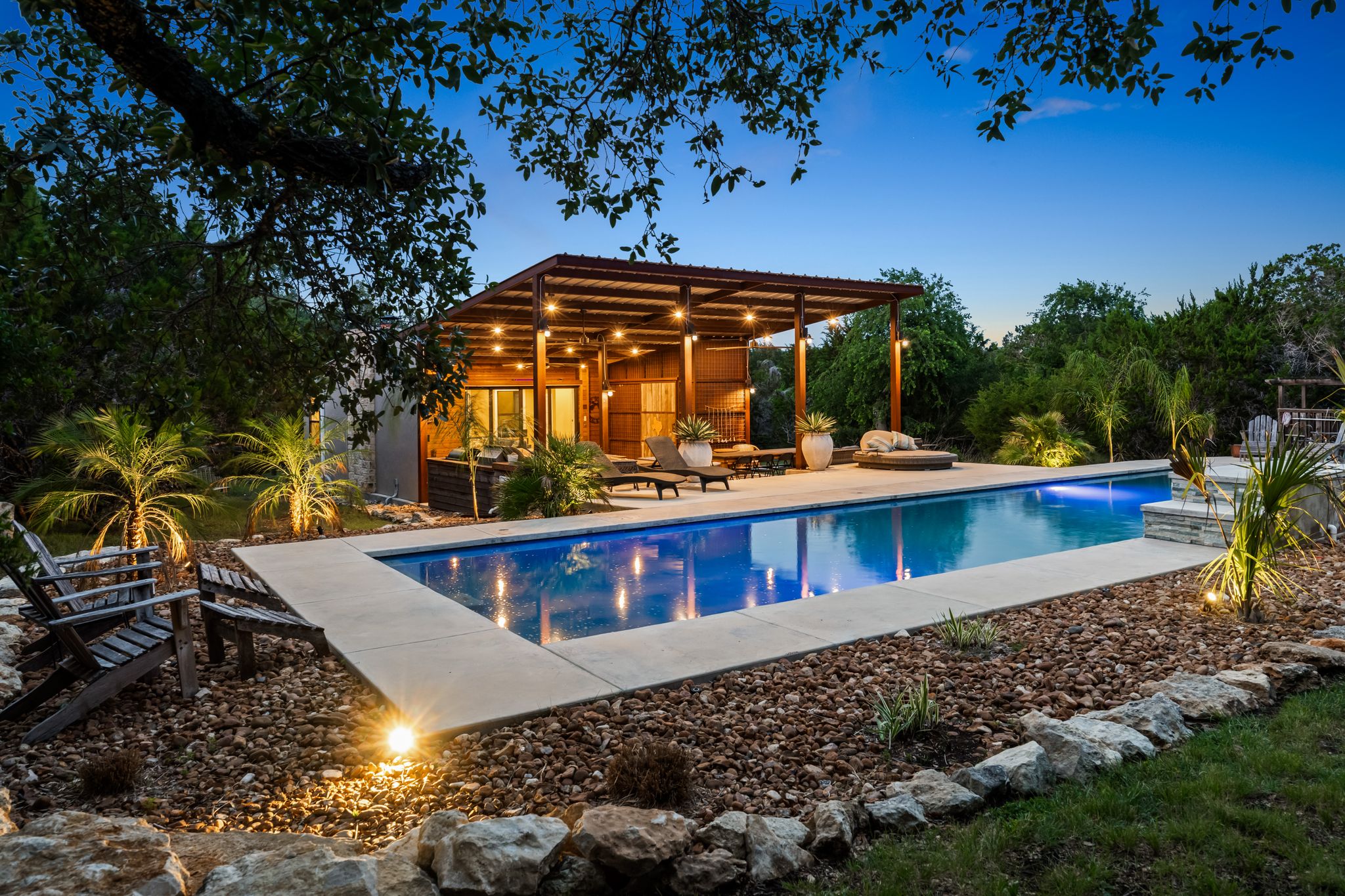 195 Desert Flower Spring Branch, TX 78070 - Photo 1 of 40 Long rectangular swimming pool with integrated lighting, surrounded by a concrete deck and a landscaped rock garden