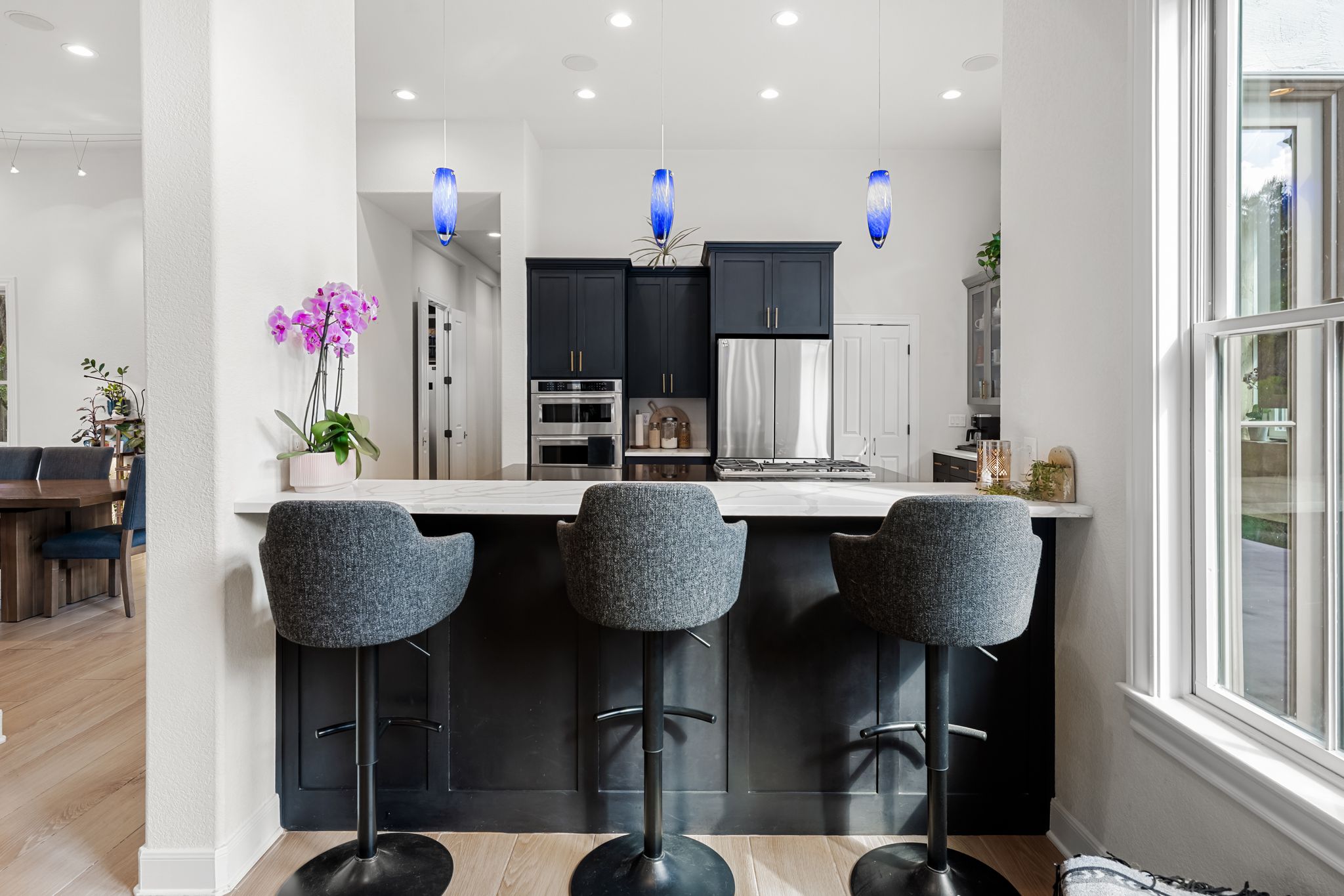 195 Desert Flower Spring Branch, TX 78070 - Photo 11 of 40 Kitchen island featuring a white countertop, dark cabinetry with brass hardware, and three pendant lights