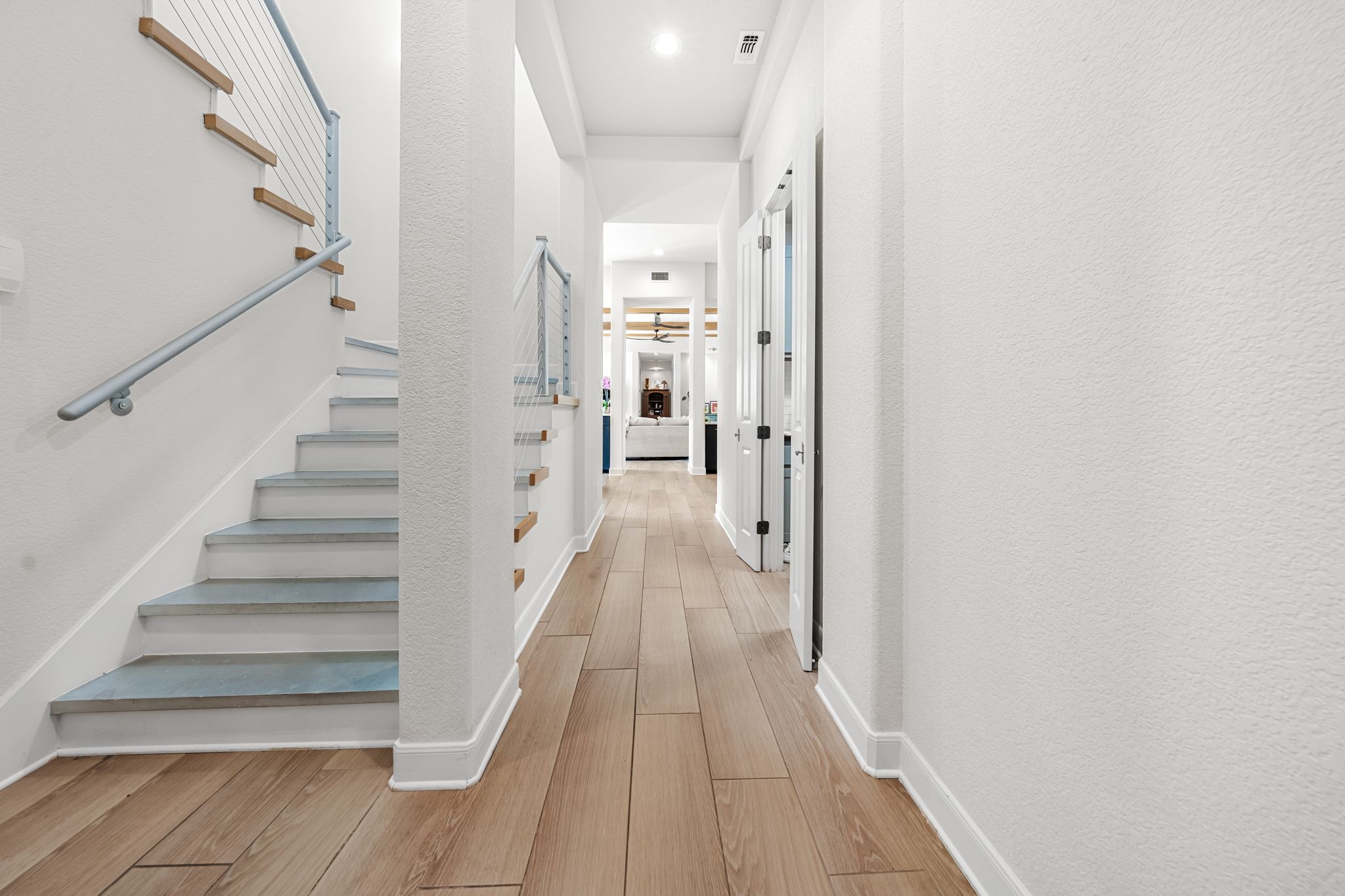 195 Desert Flower Spring Branch, TX 78070 - Photo 19 of 40 Hallway featuring wood-finish flooring, white baseboards, recessed lighting, and a modern staircase with cable railing
