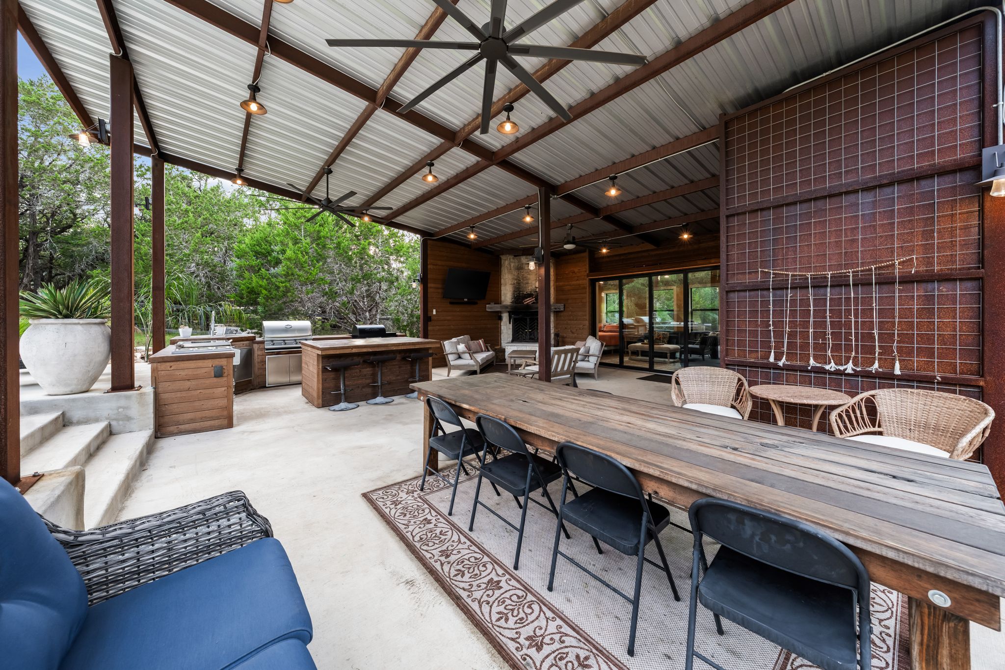 195 Desert Flower Spring Branch, TX 78070 - Photo 32 of 40 Expansive covered patio featuring a full outdoor kitchen, wood-finish dining table, ceiling fans, recessed lighting, and exposed metal framing