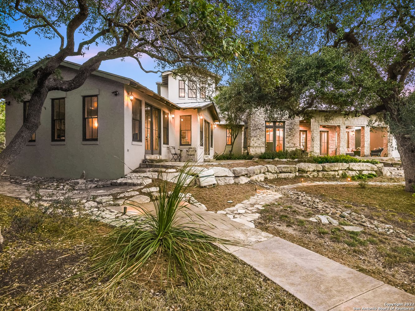 195 Desert Flower Spring Branch, TX 78070 - Photo 4 of 40 Stone and stucco exterior featuring multiple windows and doors, a second-story dormer, and a covered outdoor patio