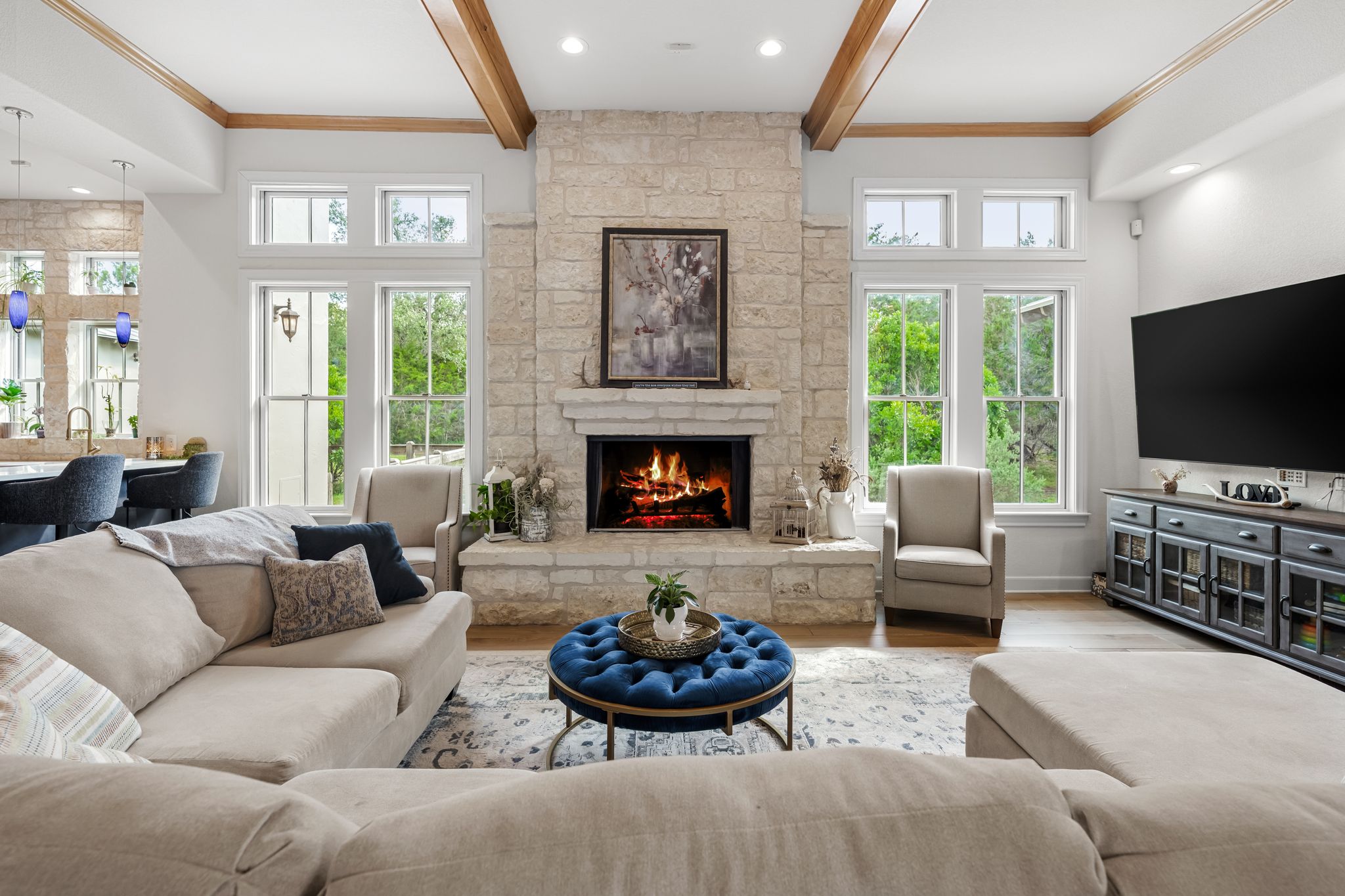 195 Desert Flower Spring Branch, TX 78070 - Photo 7 of 40 Spacious living area featuring a stone fireplace, wood-finish flooring, exposed wood ceiling beams, and abundant natural light from multiple windows