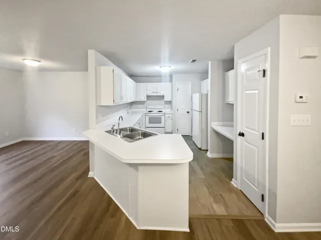 a kitchen with a sink a stove a refrigerator and white cabinets