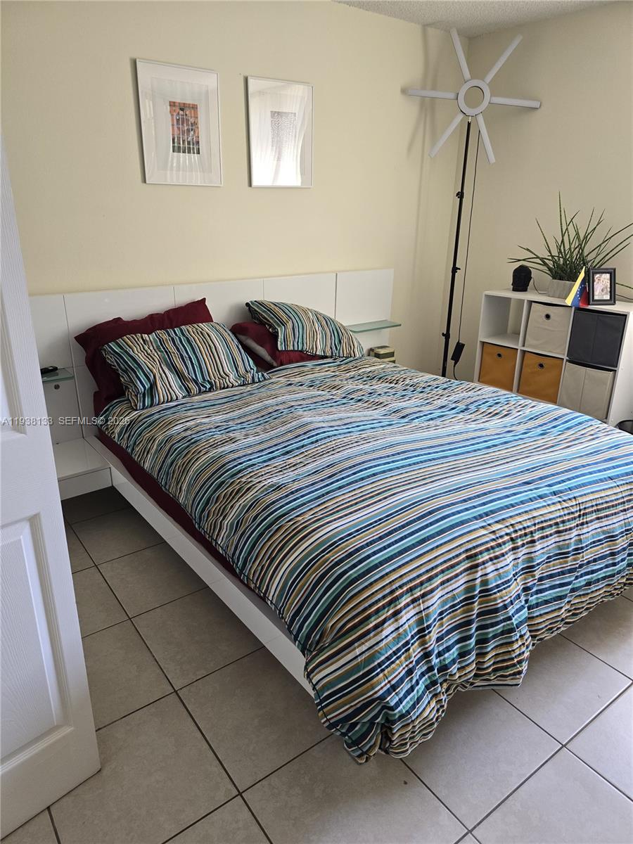 8255 Southwest 152nd Avenue, Unit E207 Miami, FL 33193 - Photo 10 of 14 a bedroom with a bed and wooden floor