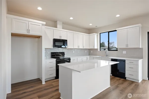 a large white kitchen with wooden floor and a sink