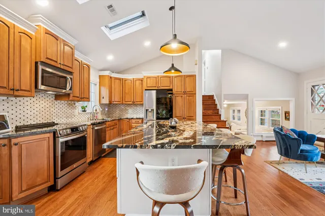 a kitchen with stainless steel appliances granite countertop wooden cabinets a stove and a sink