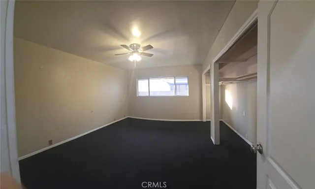 an empty room with windows and chandelier fan
