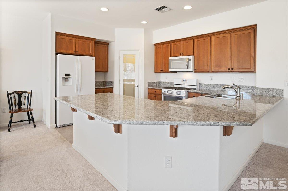 9700 Declan Drive Reno, NV 89521 - Photo 12 of 34 a kitchen with stainless steel appliances granite countertop a sink refrigerator and cabinets