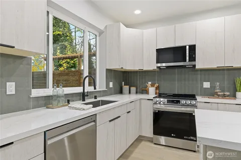 a kitchen with granite countertop a sink cabinets stainless steel appliances and a window